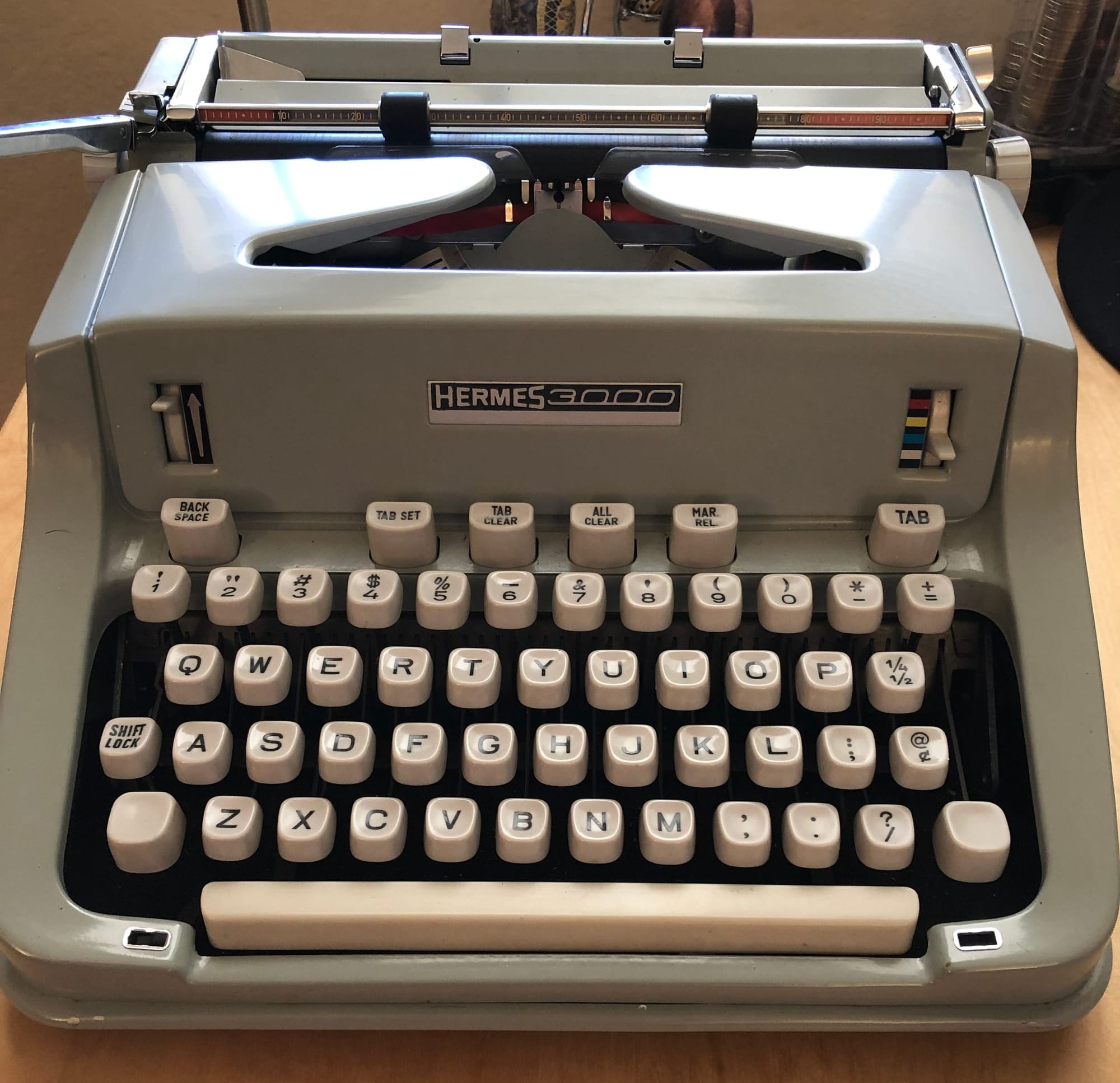 Picture of a seafoam green Hermes 3000 typewriter on a desk.
